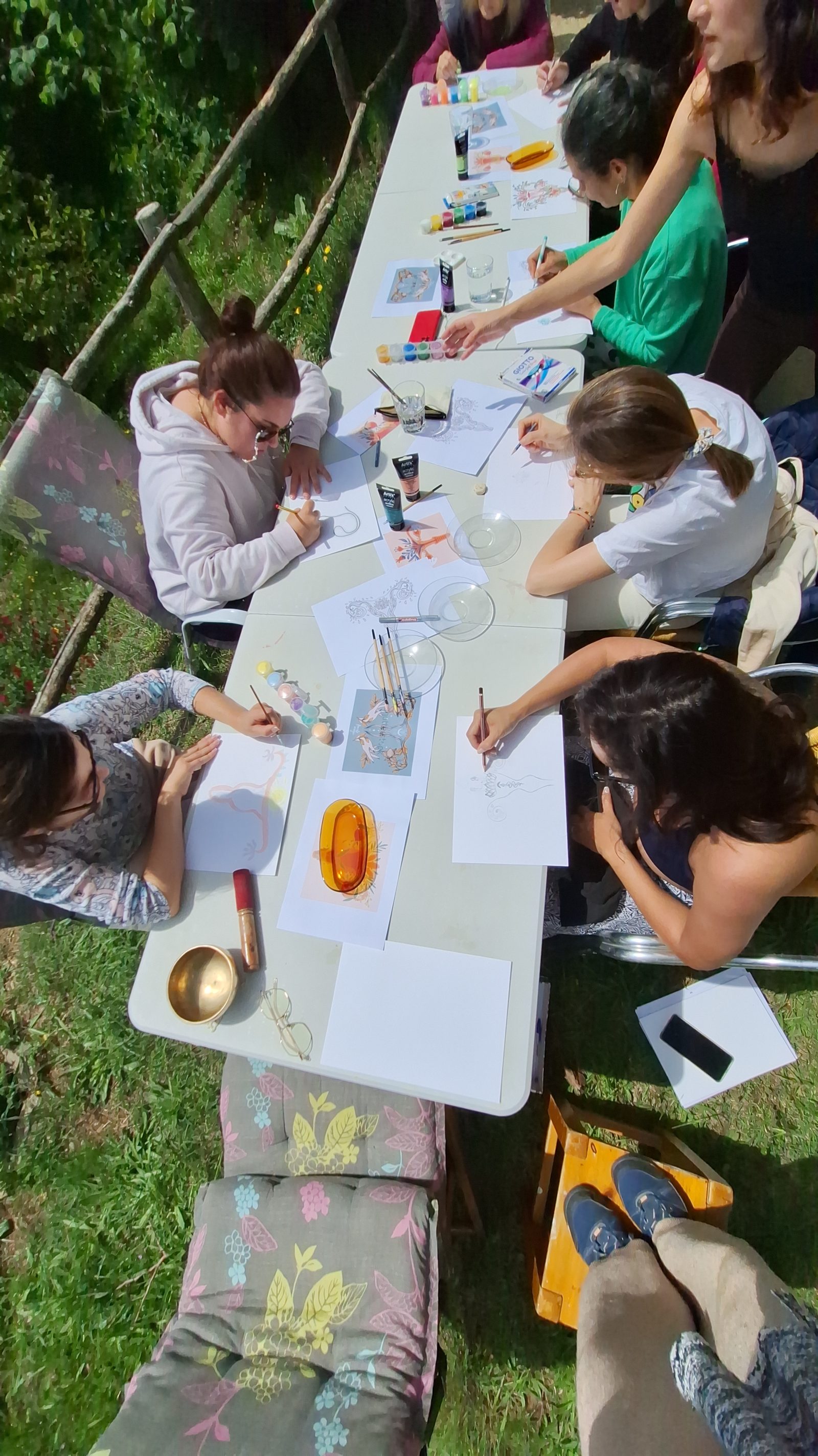 Personas creando dibujos y pinturas en una mesa al aire libre